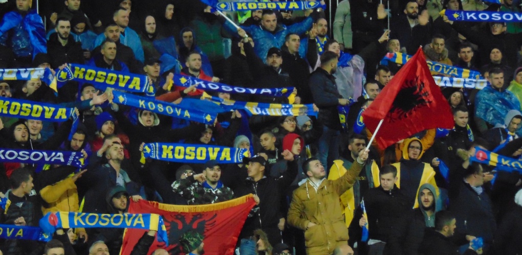 kosovo football fans wave flags in stadium